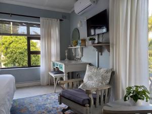a bedroom with a desk and a chair and a window at Ocean Blue Suite - Villa Roc Guesthouse in Salt Rock