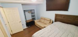 a bedroom with a bed and a chair and a door at Parson Creek Cozy suite in Fort McMurray