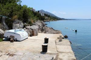 un bateau assis sur le côté d'une masse d'eau dans l'établissement Apartments by the sea Ladjin Porat, Paklenica - 17624, à Starigrad-Paklenica