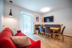 een woonkamer met een rode bank en een tafel bij Apartments Cesa Ploner in Ortisei