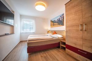 オルティゼーイにあるApartments Cesa Plonerのベッドルーム1室(ベッド1台付)、大きな木製キャビネットが備わります。
