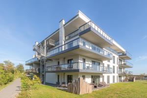 an apartment building with balconies and a lawn at Zwei Wasser - Strandhaus Alte Seefahrtschule in Wustrow