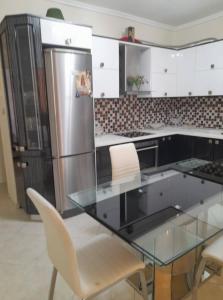 eine Küche mit einem Glastisch und einem Kühlschrank in der Unterkunft Lititsia apartment in Thessaloniki