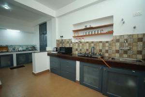 a large kitchen with blue cabinets and a sink at Ayla Homes in Madikeri