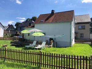 a yard with chairs and umbrellas and a building at SaidenbachHaus in Großhartmannsdorf