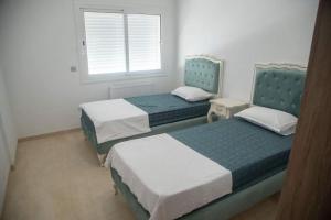 two beds in a small room with a window at Splendide appartement au PALM LAKE RESORT in Monastir