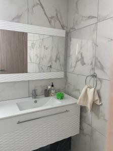 La salle de bains blanche est pourvue d'un lavabo et d'un miroir. dans l'établissement Splendide appartement au PALM LAKE RESORT, à Monastir