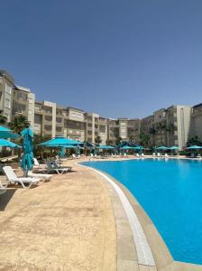 una gran piscina con sillas y sombrillas en Splendide appartement au PALM LAKE RESORT, en Monastir