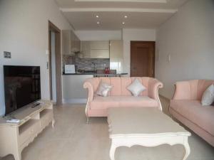 a living room with a pink couch and a tv at Splendide appartement au PALM LAKE RESORT in Monastir