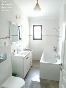 a white bathroom with a tub and a sink and a toilet at Cozy Apartment Narciselor Suceava in Ipoteşti