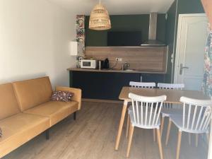 a living room with a couch and a table and chairs at Le Clos in Hucqueliers