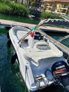 a white boat tied to a dock in the water at Yachting Residence - Private Dock, Lake Access & SPA in Lavena Ponte Tresa