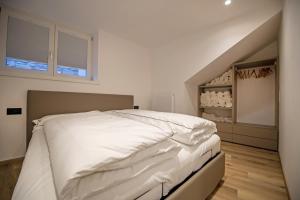 a bedroom with a white bed and a staircase at Dolomites Apartments Cesa Benedet in Santa Cristina in Val Gardena