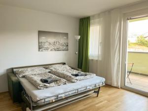 a bedroom with a bed in a room with a window at Vienna City and SPA - Modern Apartments next to Therme Wien & 15 Minutes to the City Center in Vienna