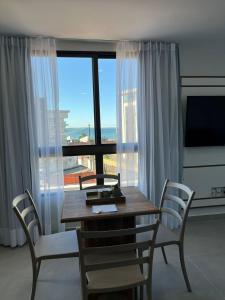 ein Esszimmer mit einem Tisch und Stühlen sowie einem großen Fenster in der Unterkunft Porto de Galinhas PORTO EXCLUSIVE BY AFT in Porto De Galinhas