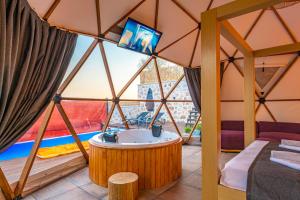 Kalkan Dome Suites & Deluxe-Glamping Holiday in Kalkan في كاس: غرفة مع حوض استحمام وتلفزيون في خيمة