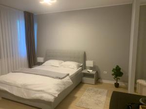 ein Schlafzimmer mit einem weißen Bett und einer Pflanze in der Unterkunft EM04- Studio premium in Târgu Jiu