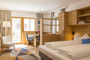 a hotel room with two beds and a desk at Residence Luzerna *** in Selva di Val Gardena