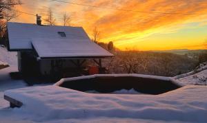 a house covered in snow with a sunset in the background at Hiška na samem in Mišji Dol +20 photos