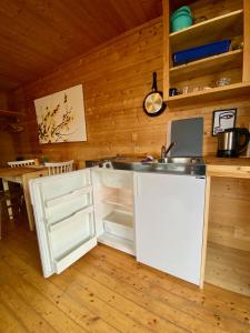 a kitchen with a sink and an open refrigerator at Haukland Camp Cabin in Leknes