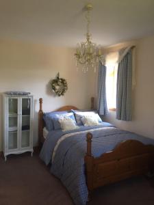 a bedroom with a bed and a chandelier and a window at Cleriach Cottage in Milton of Auchinhove