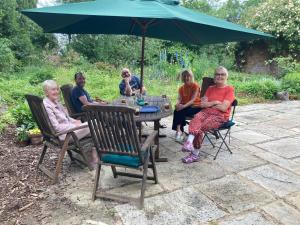 een groep vrouwen die rond een tafel zitten onder een paraplu bij Sans, Souci. @ Mill House in Horncastle