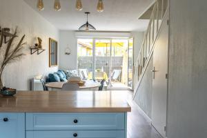 a kitchen with blue cabinets and a living room at LES RENARDS - Charmante petite maison au port de la Teste in La Teste-de-Buch
