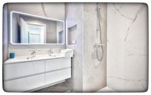 a bathroom with a sink and a shower with a mirror at Le Vallaya Suites & Spa in Menton