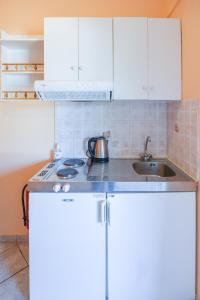 a kitchen with white cabinets and a sink at Villa Myrto in Pelekas