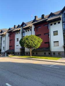 ein Gebäude mit einem Baum in der Mitte einer Straße in der Unterkunft Bee's Place Holiday Home Kranjska Gora in Kranjska Gora