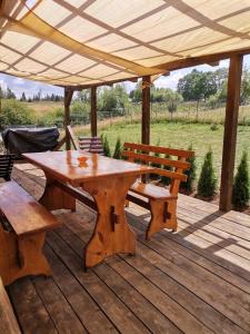 a wooden picnic table and benches on a wooden deck at Căsuța de munte in Mărişel