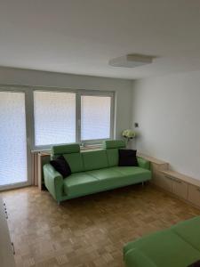 a living room with a green couch and windows at Bee's Place Holiday Home Kranjska Gora in Kranjska Gora