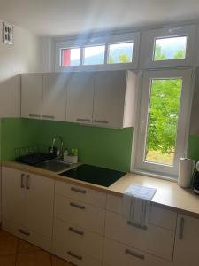 a kitchen with white cabinets and a sink and two windows at Bee's Place Holiday Home Kranjska Gora in Kranjska Gora