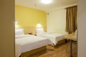 a hotel room with two beds and a desk at 7Days Inn Shenzhen Shajing Shiming Square in Bao'an