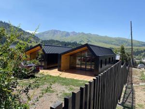 una casa en una colina con una valla de madera en Peak Lodge Jyrgalan en Dzhergalan