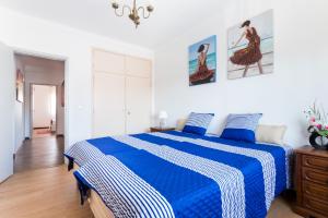 uma cama azul e branca num quarto branco em Casa do Faria em Caminha