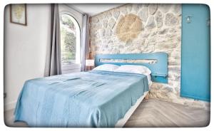 a blue bed in a room with a stone wall at Le Vallaya Suites & Spa in Menton