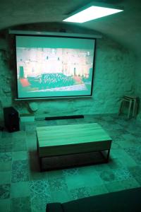Pokój z telewizorem z płaskim ekranem na kamiennej ścianie w obiekcie Maison 3 chambres 100m du Théâtre Antique avec salle cinéma w Orange