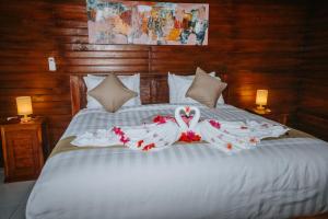 Una cama blanca con dos cisnes. en Kurnia Guest House & Spa en Nusa Penida