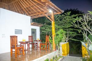 a patio with wooden tables and chairs and trees at Kurnia Guest House & Spa in Nusa Penida
