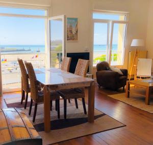 een woonkamer met een tafel en stoelen en de oceaan bij "BELLEVUE" Magnifique appartement vue sur mer et face à Nausicàa in Boulogne-sur-Mer