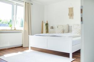 a white bed in a white bedroom with a window at Ferienwohnung Landparadies im Sauerland in Bestwig