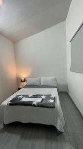 a bedroom with a bed and a white wall at Aparta estudio amoblado 3 Medellin, San joaquin in Medellín