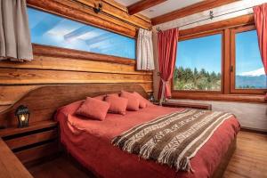 a bedroom with a red bed with a large window at Hill & Sky Lodge in Pucón