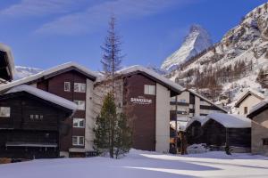 un hôtel dans les montagnes avec de la neige au sol dans l'établissement Hotel Sarazena, à Zermatt