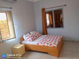 a bedroom with a bed with a window and a window at Appartement hôte + in Ouagadougou