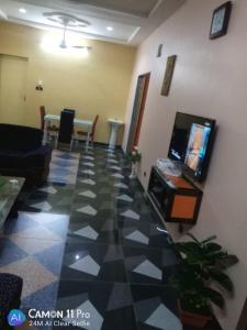 a living room with a tv and a tiled floor at Appartement hôte + in Ouagadougou