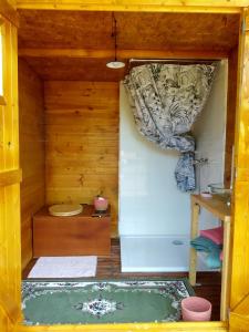 uma pequena casa de banho com banheira numa casa de madeira em Yourtes Lacroutz em Nassiet