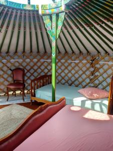 a room with a bed and a chair in a yurt at Yourtes Lacroutz in Nassiet