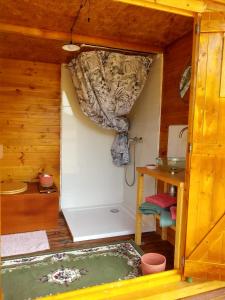 a small room with a shower in a wooden house at Yourtes Lacroutz in Nassiet